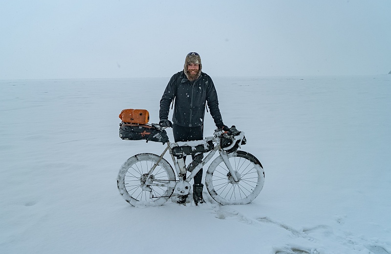 Jonas Deichmann präsentiert sein schneebedecktes Fahrrad.
